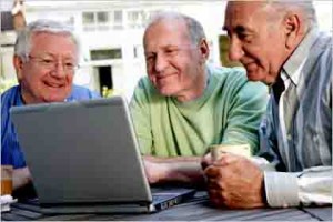 Three senior men looking at laptop computer screen, smiling, close-up